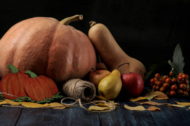 Осенняя композиция с тыквой и осенними фруктами с яблоками и грушами на темно-синем столе и на черном фоне
 - Фото, изображение