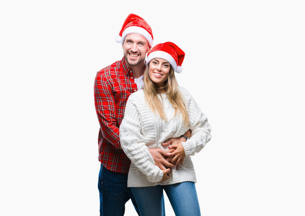 愛の顔に幸せとクールな笑顔で孤立した背景にクリスマスの帽子をかぶっての若いカップル。幸運な人. - 写真・画像