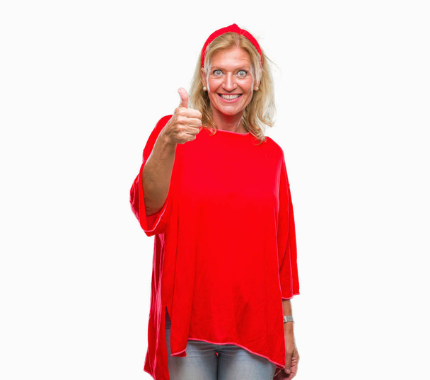 Middle age blonde woman over isolated background doing happy thumbs up gesture with hand. Approving expression looking at the camera with showing success. - Photo, Image