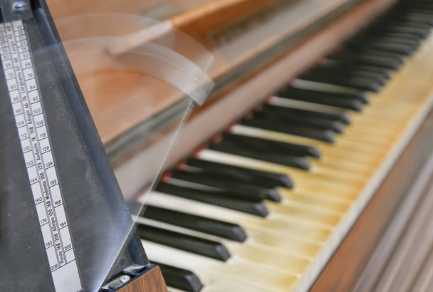 Античний метроном відзначає ритм музики на старому дерев'яному піаніно
 - Фото, зображення