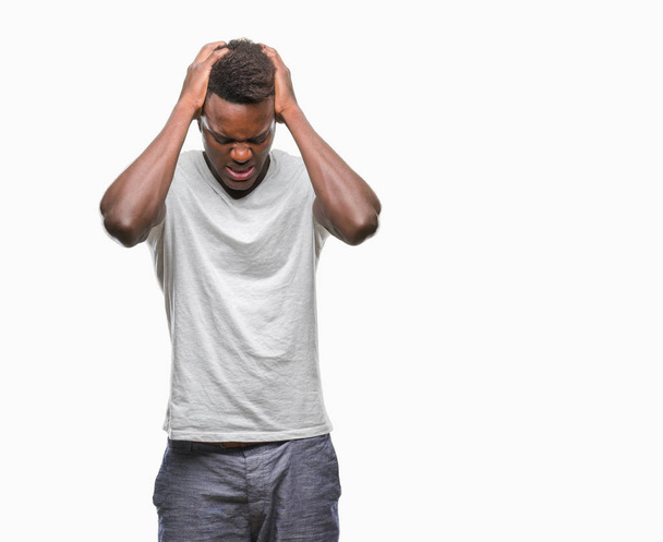 junger afrikanisch-amerikanischer Mann mit isoliertem Hintergrund, der unter Kopfschmerzen leidet, verzweifelt und gestresst wegen Schmerzen und Migräne. Hände auf den Kopf. - Foto, Bild