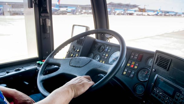 Nahaufnahme: Fahrer fährt Passagierbus auf Landebahn auf Flugzeug zu - Foto, Bild