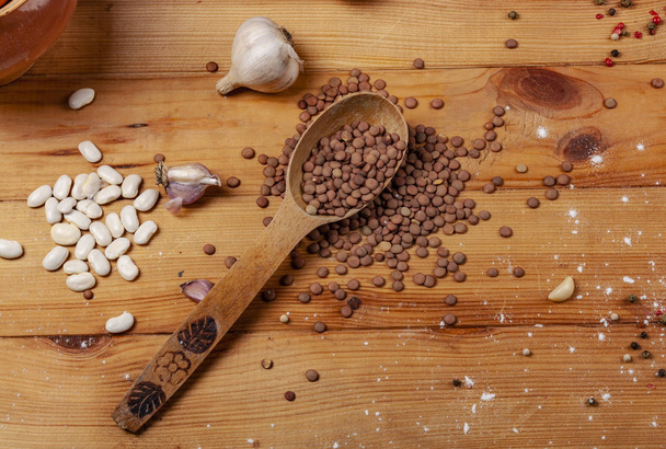 Kidney beans, garlic, and lentils on a wooden table. - Photo, image