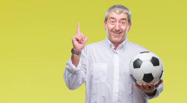 Bell'uomo anziano che tiene il pallone da calcio su sfondo isolato sorpreso da un'idea o una domanda che punta il dito con la faccia felice, numero uno
 - Foto, immagini