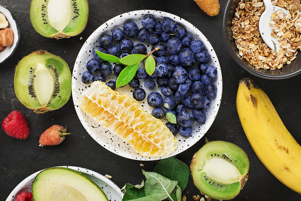Ingredients for healthy breakfast meals: raspberries, blueberries, nuts, orange, bananas, grapes blue, green apples kiwi Top View - Фото, изображение