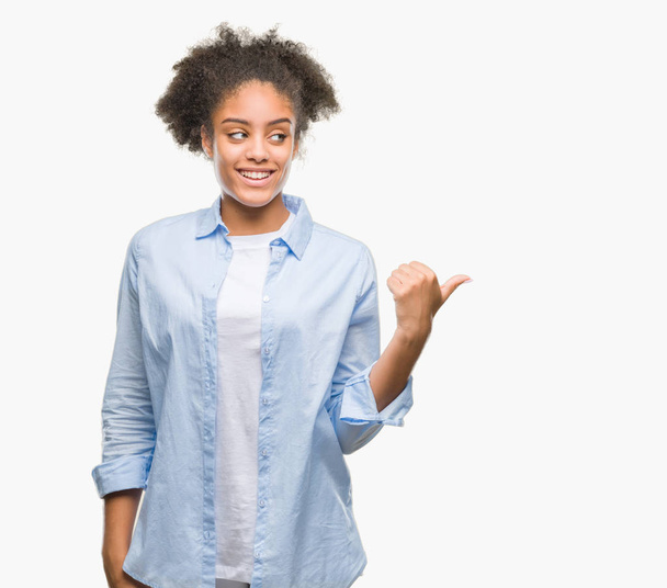 Jeune femme afro-américaine sur fond isolé souriant avec le visage heureux regardant et pointant vers le côté avec le pouce vers le haut
. - Photo, image
