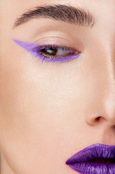 Close-up of a woman's beauty with fashionable make-up. Lilac color shooter and lipstick for lips in tone. Cosmetology, cosmetics. Long eyelashes and thick eyebrows, perfectly clean skin of the face - Photo, image