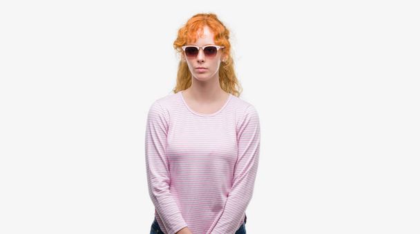junge rothaarige Frau mit Sonnenbrille und selbstbewusstem Gesichtsausdruck, die ernsthaft denkt - Foto, Bild