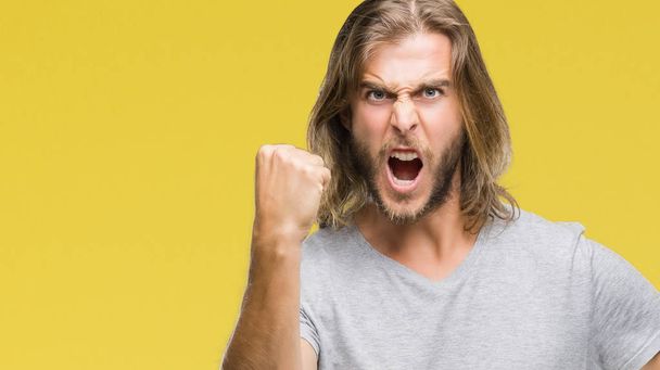 Young handsome man with long hair over isolated background holding football ball annoyed and frustrated shouting with anger, crazy and yelling with raised hand, anger concept - Photo, Image
