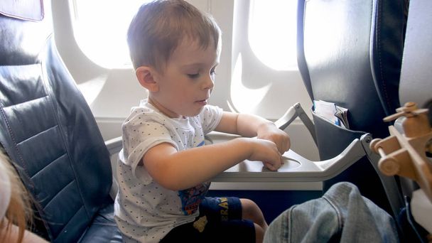 Portrait of little toddler boy sitting in airplane and playing with toys - Photo, Image
