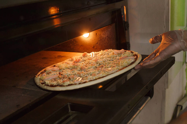 Deniz ürünleri pizza fırın içine koyarak - Fotoğraf, Görsel