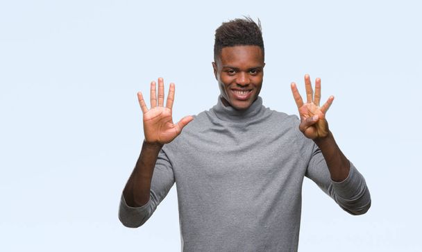 Νεαρός αφρικανική αμερικανική άνθρωπος πέρα από το απομονωμένο υπόβαθρο δείχνει και δείχνει προς τα επάνω με τα δάχτυλα τον αριθμό εννέα ενώ χαμογελώντας αυτοπεποίθηση και χαρούμενοι. - Φωτογραφία, εικόνα
