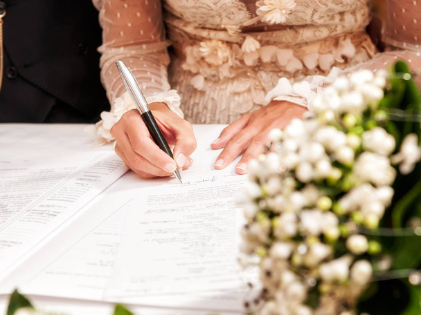 Λεπτομέρεια από το χέρι του μια νύφη που υπογράφει την πράξη γάμου - Φωτογραφία, εικόνα