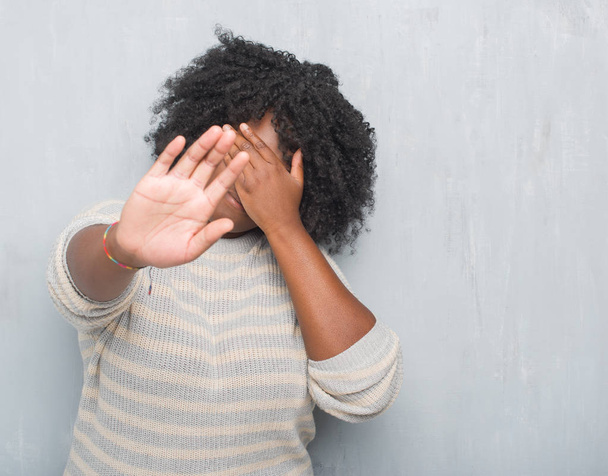 Молода афроамериканка плюс розмір жінка над сірою гранжевою стіною в светрі, що закриває очі руками і робить стоп жест з сумним і страховим виразом. Збентежена і негативна концепція
. - Фото, зображення