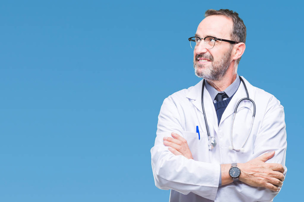 Middle age senior hoary doctor man wearing medical uniform isolated background smiling looking side and staring away thinking. - Photo, Image