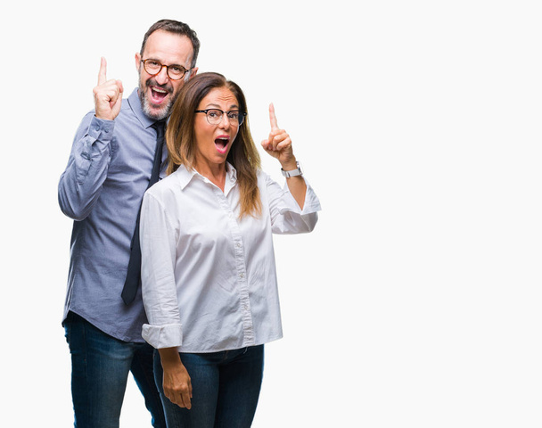 Hispanic echtpaar van middelbare leeftijd in hou van bril over geïsoleerde achtergrond vinger omhoog met succesvolle idee. Verlaten en gelukkig. Nummer één. - Foto, afbeelding