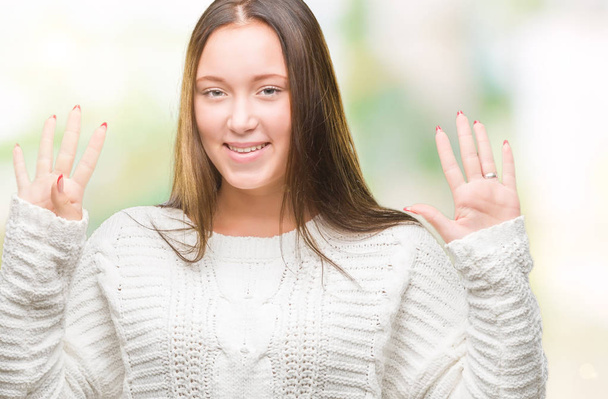 Νεαρή όμορφη γυναίκα Καυκάσιος φορώντας χειμώνα πουλόβερ πέρα από το απομονωμένο υπόβαθρο δείχνει και δείχνει προς τα επάνω με τα δάχτυλα τον αριθμό εννέα ενώ χαμογελώντας αυτοπεποίθηση και χαρούμενοι. - Φωτογραφία, εικόνα