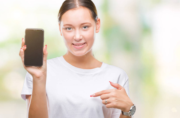 Jonge mooie Kaukasische vrouw weergegeven: smartphone scherm over geïsoleerde achtergrond met verrassing gezicht wijzende vinger naar zichzelf - Foto, afbeelding
