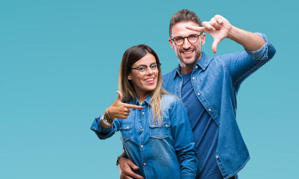 Young couple in love wearing glasses over isolated background smiling making frame with hands and fingers with happy face. Creativity and photography concept. - Photo, Image