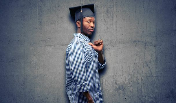 Νεαρή αφρικανική μεταπτυχιακός φοιτητής μαύρο ο άνθρωπος υπερήφανοι, ενθουσιασμένοι και αλαζονική, επισημαίνοντας με νίκη πρόσωπο - Φωτογραφία, εικόνα