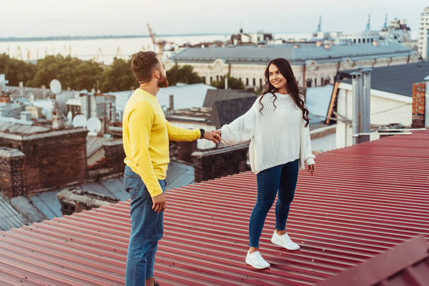 Loving young couple is standing on the roof of the house. - Photo, Image