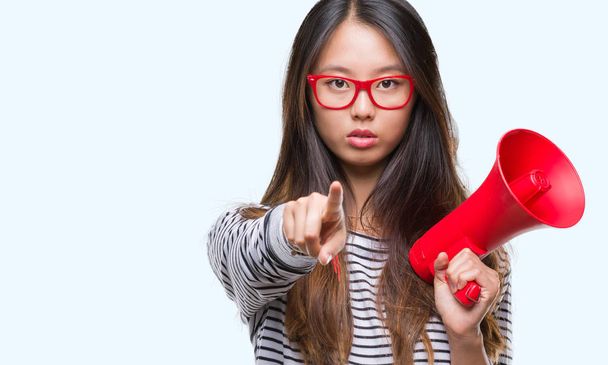Young asian woman holding megaphone over isolated background pointing with finger to the camera and to you, hand sign, positive and confident gesture from the front - Φωτογραφία, εικόνα