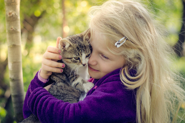 encantadora chica rubia sosteniendo un gato esponjoso y abrazos juntos
 - Foto, Imagen