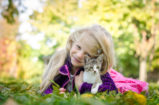bella ragazza bionda con gatto e sdraiati insieme sull'erba in autunno tempo
 - Foto, immagini
