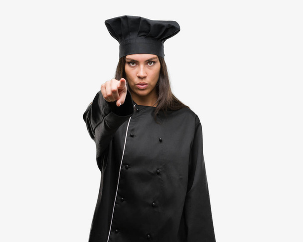 Młody kucharz hiszpanin kobieta noszenia chef jednolite, wskazując palcem do aparatu i do Ciebie, ręcznie zarejestrować, gest pozytywny i pewnie z przodu - Zdjęcie, obraz