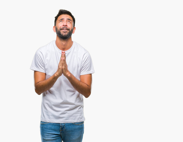 Взрослый латиноамериканец на изолированном фоне просит и молится руками вместе с выражением надежды на лице очень эмоциональным и беспокойным. Просил прощения. Концепция религии
. - Фото, изображение