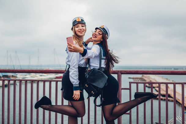 女子大学生を 2 つ海洋アカデミーの制服を着て海で selfie の。桟橋上で楽しんで幸せな友達 - 写真・画像