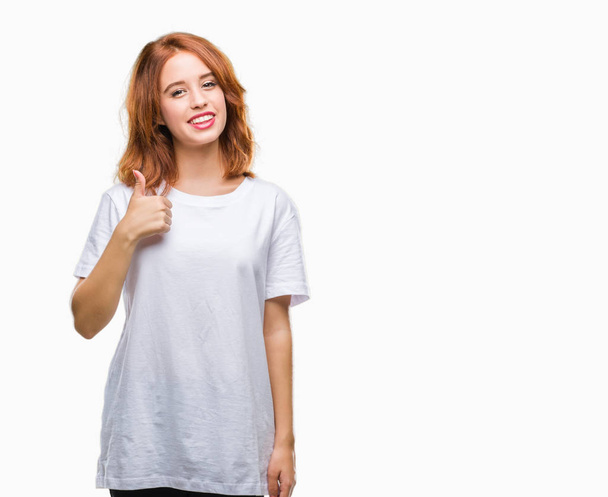 Young beautiful woman over isolated background doing happy thumbs up gesture with hand. Approving expression looking at the camera with showing success. - Valokuva, kuva