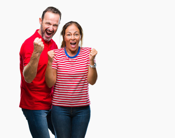 Middle age hispanic couple in love over isolated background celebrating surprised and amazed for success with arms raised and open eyes. Winner concept. - Фото, изображение