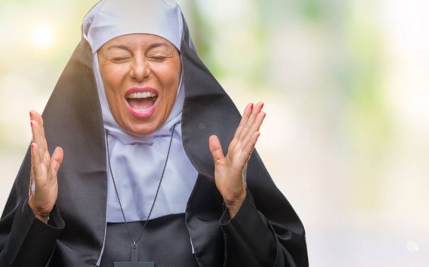 Középkorú idősebb keresztény katolikus apáca nő több mint elszigetelt, háttér ünneplő őrült és őrült, a siker a karok felemelte, és csukott szemmel, izgatott sikoltozik. Győztes koncepció - Fotó, kép
