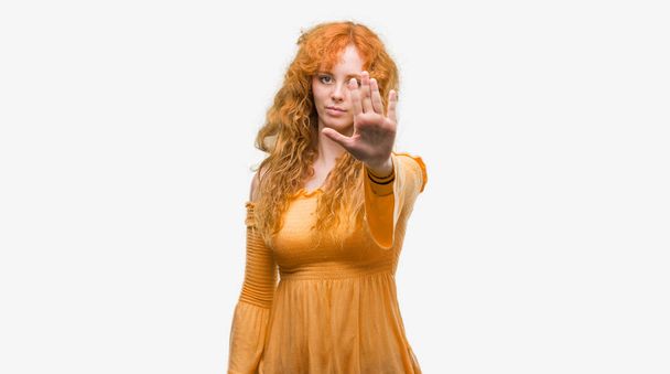 Young redhead woman doing stop sing with palm of the hand. Warning expression with negative and serious gesture on the face. - Photo, Image