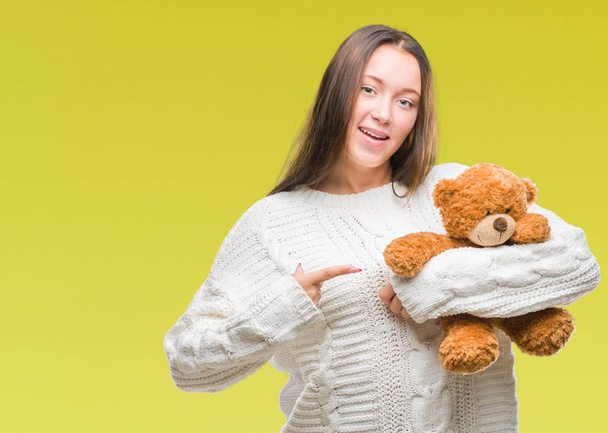 Young caucasian woman holding teddy bear over isolated background very happy pointing with hand and finger - Фото, изображение