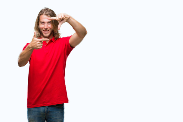 Young handsome man with long hair over isolated background smiling making frame with hands and fingers with happy face. Creativity and photography concept. - Photo, Image
