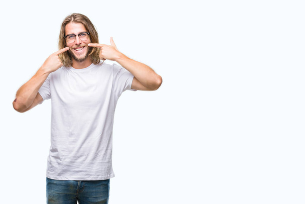 Young handsome man with long hair wearing glasses over isolated background smiling confident showing and pointing with fingers teeth and mouth. Health concept. - Photo, Image