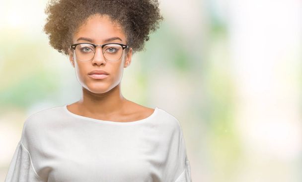 Yüzünde ciddi bir ifade ile izole arka plan üzerinde gözlük takan genç afro Amerikalı kadın. Basit ve doğal kameraya bakıyor. - Fotoğraf, Görsel