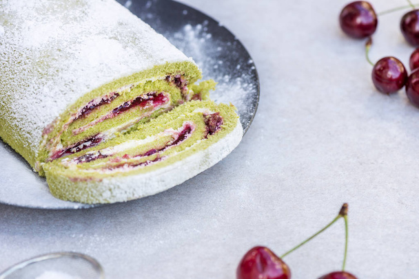 A delicate roulade of Matcha tea sponge, filled with fruity Morello cherry compote and cream - Photo, Image