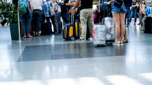 Πόδια ανθρώπων και βαλίτσα στον όροφο στο διεθνές τερματικό σταθμό του αεροδρομίου - Φωτογραφία, εικόνα