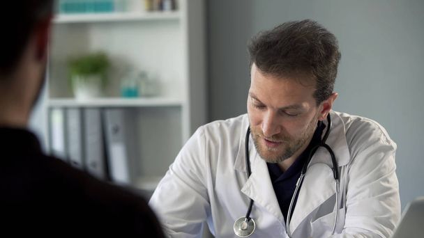 Male therapist chatting with patient making notes, healthcare and medicine - Foto, Imagem