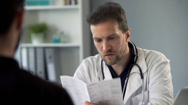 Therapist reading patients test results making diagnosis, healthcare medicine - 写真・画像