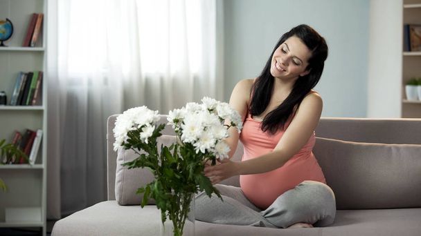 Lovely pregnant lady decorating house with nice flowers, aesthetic enjoyment - Foto, immagini