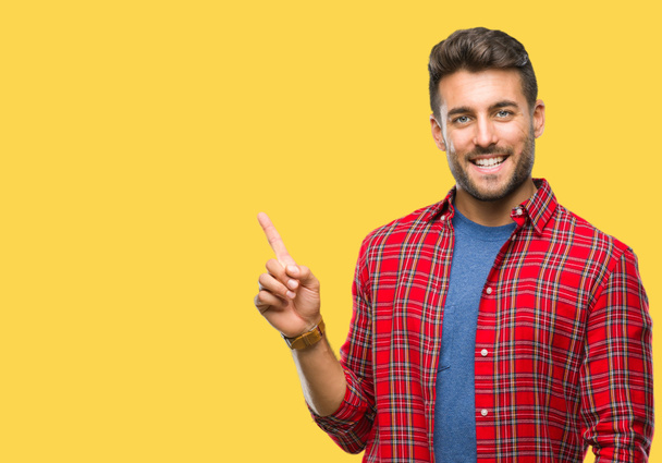 Young handsome man over isolated background with a big smile on face, pointing with hand and finger to the side looking at the camera. - Photo, Image