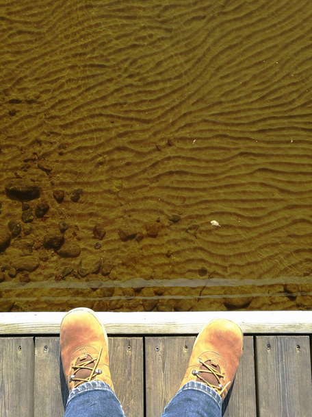 voeten in suède schoenen op een houten dok - Foto, afbeelding