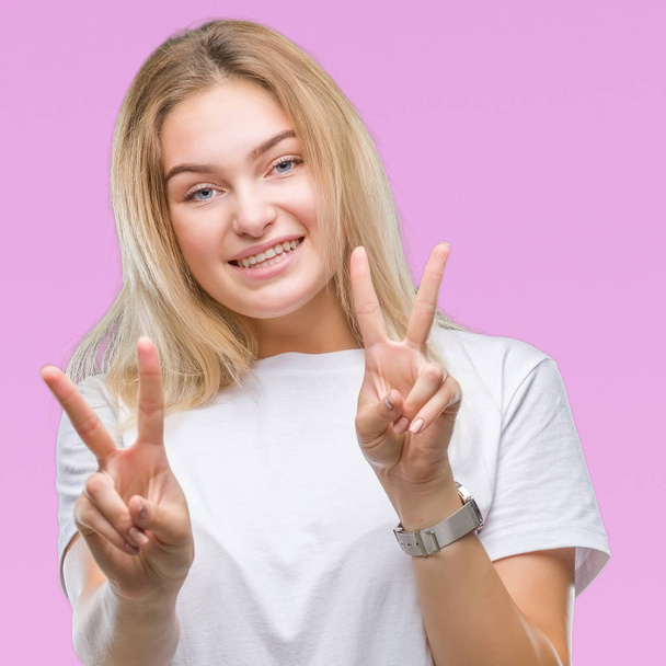 Young caucasian woman over isolated background smiling looking to the camera showing fingers doing victory sign. Number two. - Фото, зображення