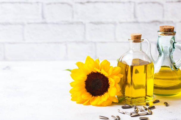Food diet and nutrition concept. Assortment of fresh organic extra virgin sunflower oil in bottles with flowers on a white kitchen table. Copy space background - Photo, Image