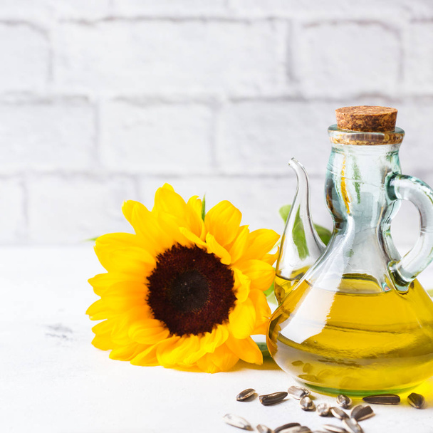Food diet and nutrition concept. Assortment of fresh organic extra virgin sunflower oil in bottles with flowers on a white kitchen table. Copy space background - Photo, Image