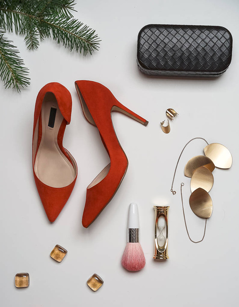 Flat lay to new year and christmas party outfit composition red shoes accessories jewelry clutch fir tree with balls white background. Party date night conception. Top view, vertical, horizontal - 写真・画像